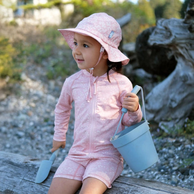 JAN & JUL Kids Cotton Floppy Hat Pink Prairie, toddler outdoors in pink floral hat with chin strap, carrying a blue bucket