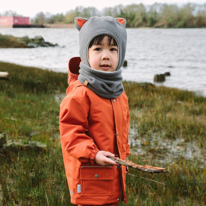 Jan & Jul Kids Fleece Animal Grey Fox hat with neck warmer, toddler outdoors by a lake, holding a twig.