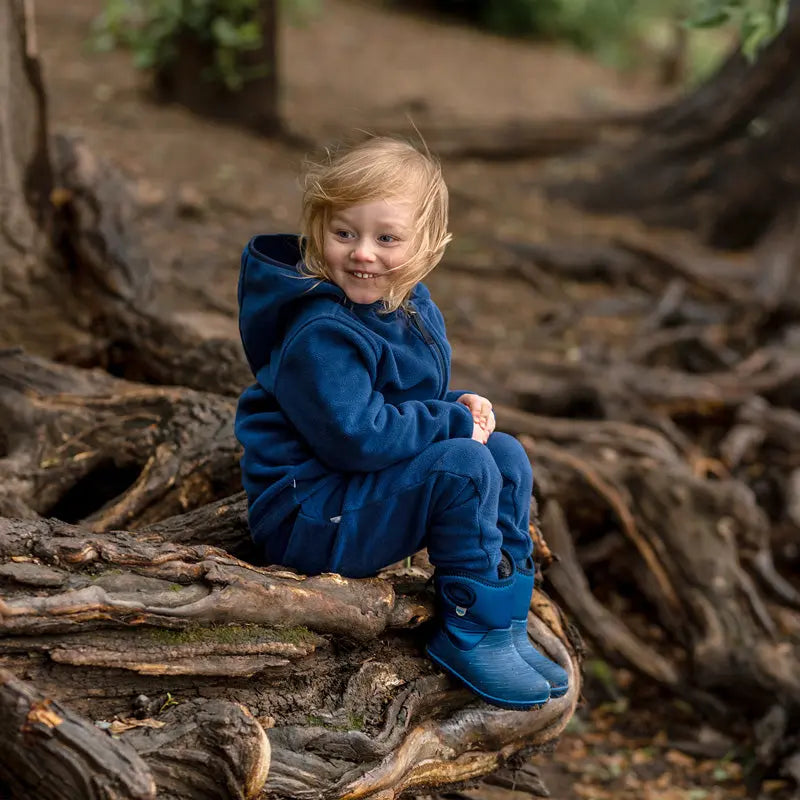 Jan & Jul Kids Fleece Jacket Navy; a toddler sits on tree roots outdoors, smiling in cozy navy fleece.