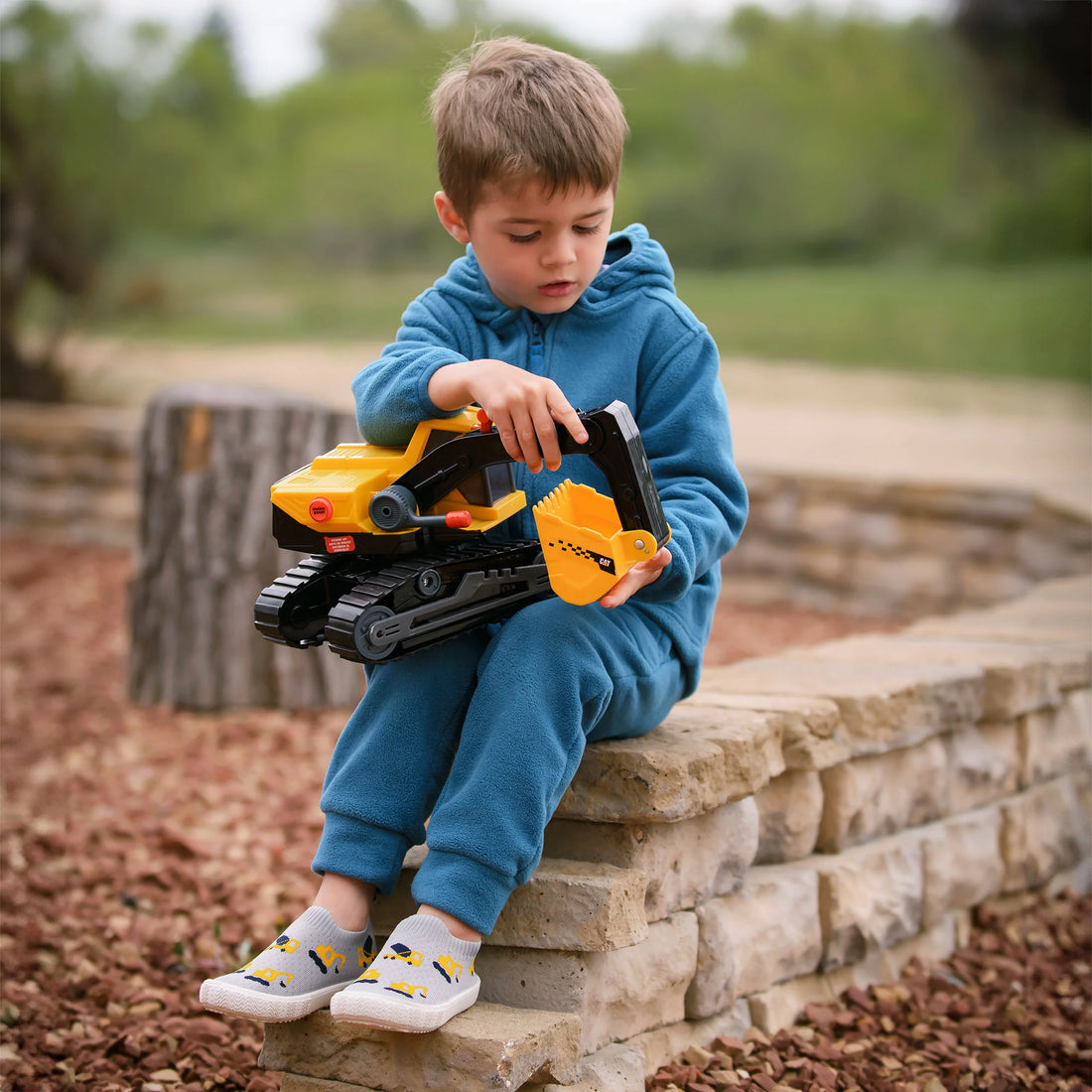 Jan & Jul Kids Graphic Slip-On Shoes - Grey Construction - child wearing Grey Construction shoes while playing with a toy truck