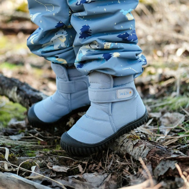 Jan & Jul Kids Insulated Ankle Boots Dusty Blue: a toddler steps through forest leaves in padded, waterproof boots.