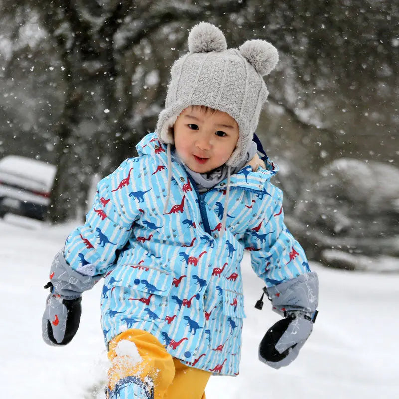 JAN & JUL Kids Knitted Beanie Hat Cream Bear, toddler wearing cream knit with twin pom-poms and bear ears in snowfall.