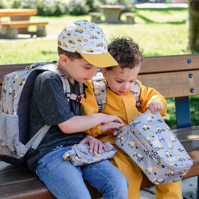 Jan & Jul Kids Lunch Bag Grey Construction pattern; two children with matching backpacks on a park bench
