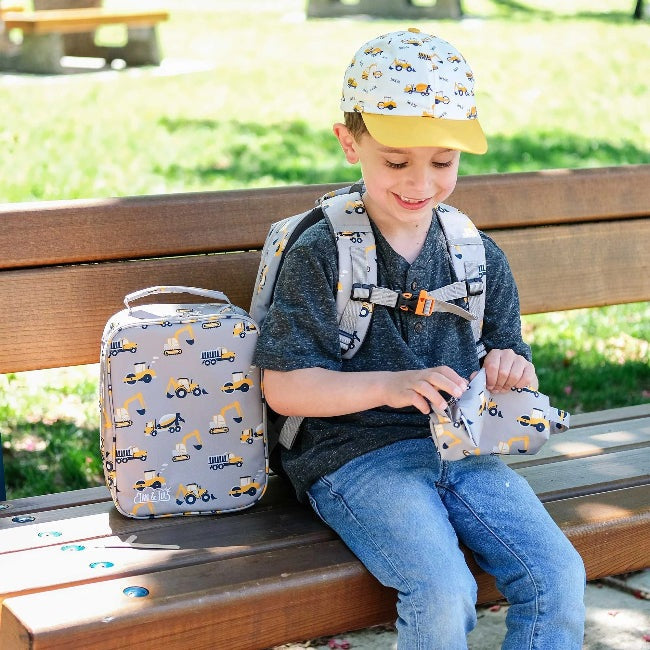 JAN & JUL kids lunch bag in grey construction print with yellow accents, shown with the matching backpack
