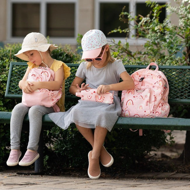 Jan & Jul Kids Pencil Case Pink Rainbow, two pink rainbow cases on a bench with two kids.