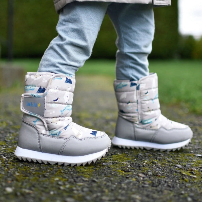 Jan & Jul Kids Tall Puffy Winter Boots Polar Pals worn by a toddler walking outdoors in quilted gray boots with rugged white soles.