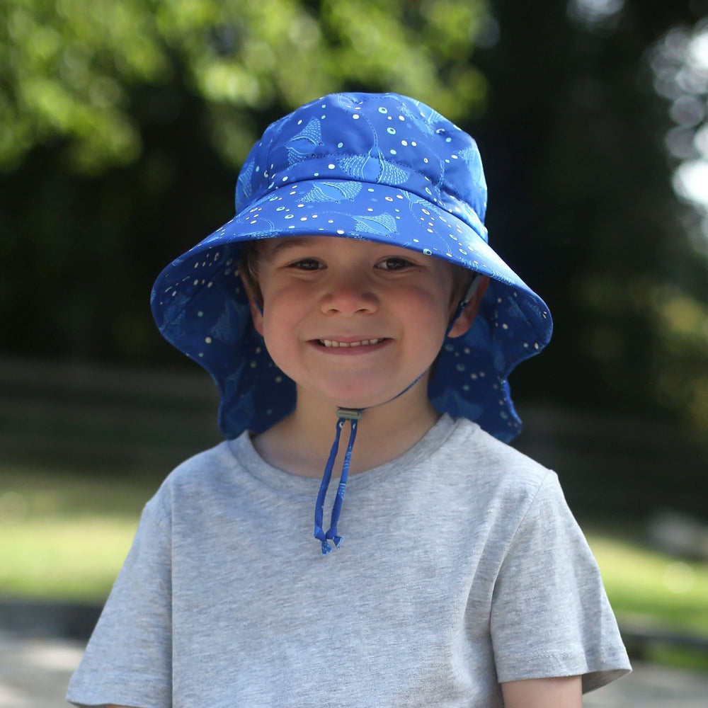 Jan & Jul Kids Water Repellent Adventure Hats Manta Ray, blue print, child smiling outdoors wearing the hat.