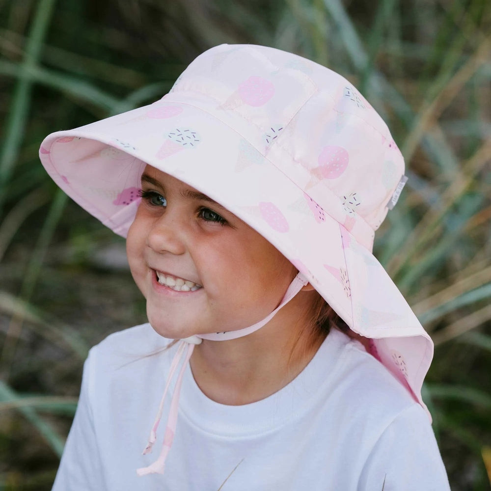 JAN & JUL Kids Water Repellent Adventure Hat Pink Ice Cream on a smiling toddler outdoors, wide brim shielding sun.