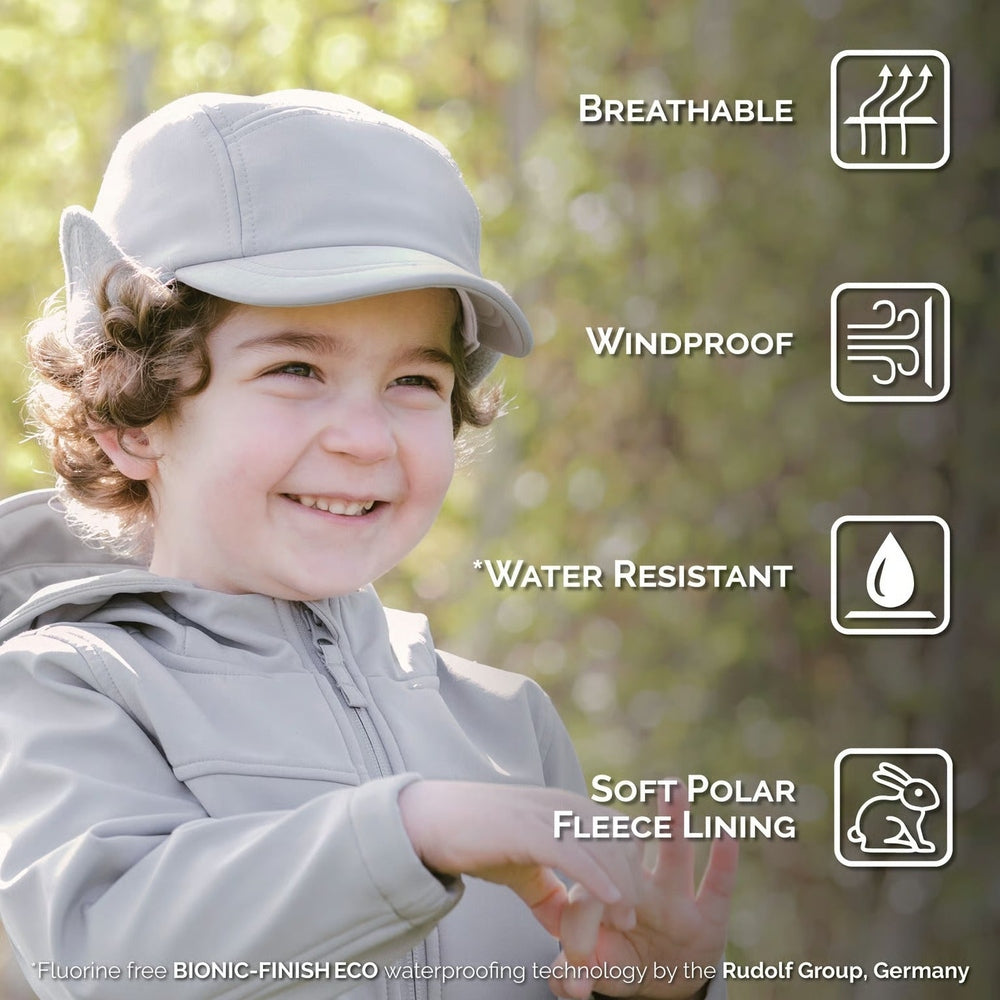 JAN & JUL Kids Water Resistant Softshell Cap Grey on a smiling child outdoors, showing breathable, windproof, fleece-lined comfort.