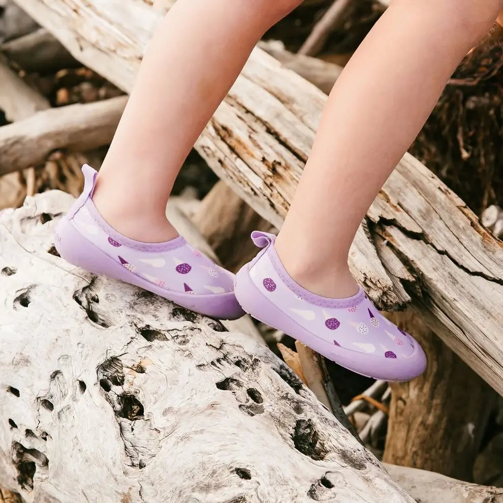 JAN & JUL Kids Water Shoes Lavender Ice Cream; lavender water shoes with ice-cream pattern, toddler stepping across driftwood.