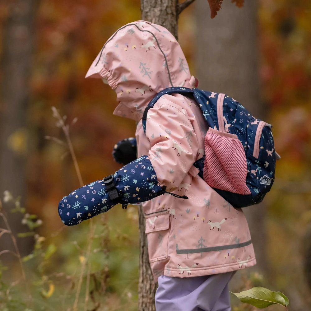 JAN & JUL Kids Waterproof Mittens Navy Forest; child in pink coat grips a tree trunk in autumn woods.