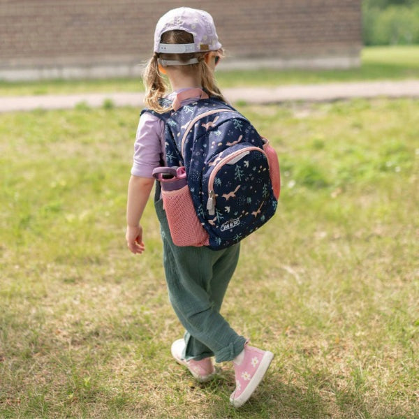 JAN & JUL Mini Backpack in navy star print with pink side pockets; child walks on grass wearing it.