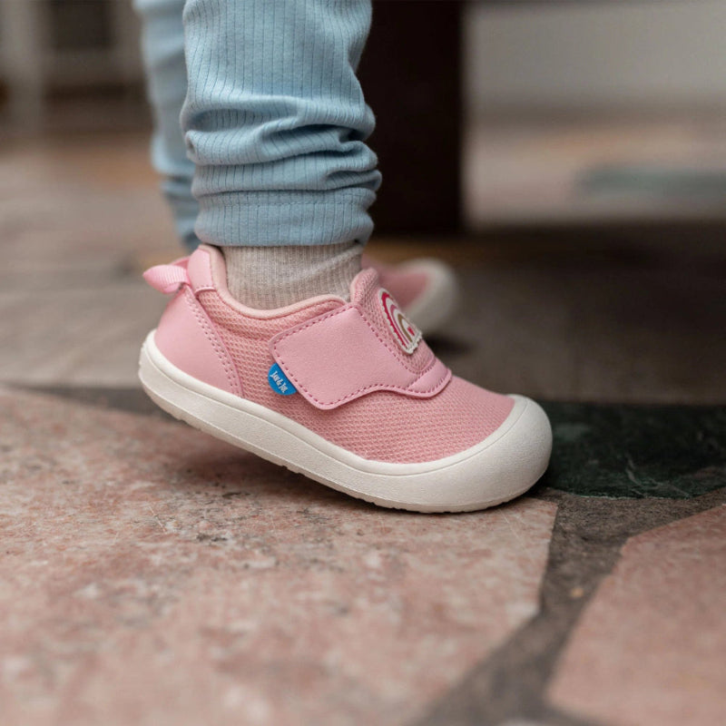 Jan & Jul Mini-Flyer toddler sneakers in pink rainbow with Velcro strap, child stepping on tiled floor