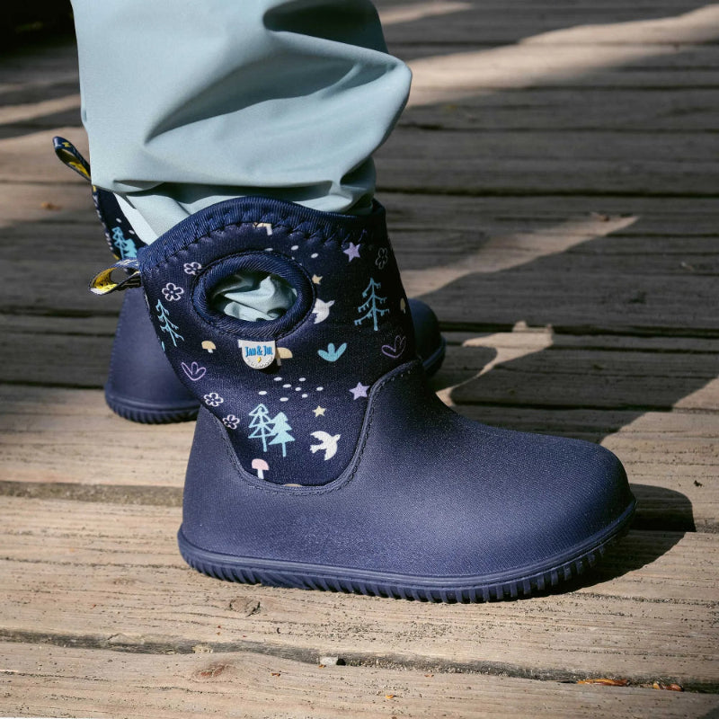 JAN & JUL Toasty Dry Lite Winter Boots Navy Forest for toddlers, navy waterproof boots with forest print, shown on a wooden deck.