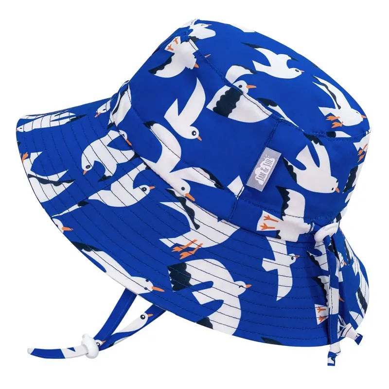 Jan & Jul Water Repellent Bucket Hats Seagull in blue with white seabirds; toddler explores outdoors with chin strap secured.