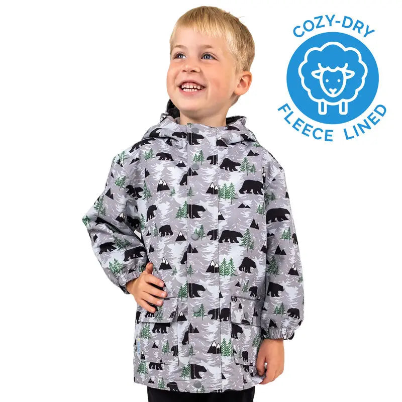 JAN & JUL Waterproof Cozy Dry Rain Jacket Bear in grey bear-print with fleece lining, worn by a smiling kid.