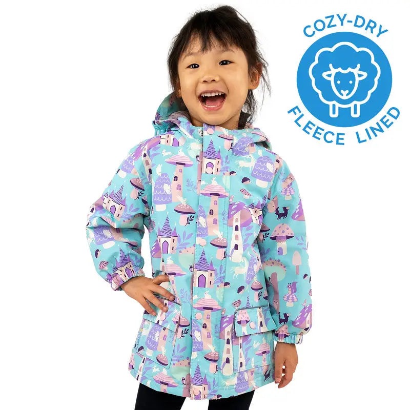 Jan & Jul Waterproof Cozy Dry Rain Jacket Enchanted for kids, light blue fleece-lined coat with castle print worn by a smiling girl.