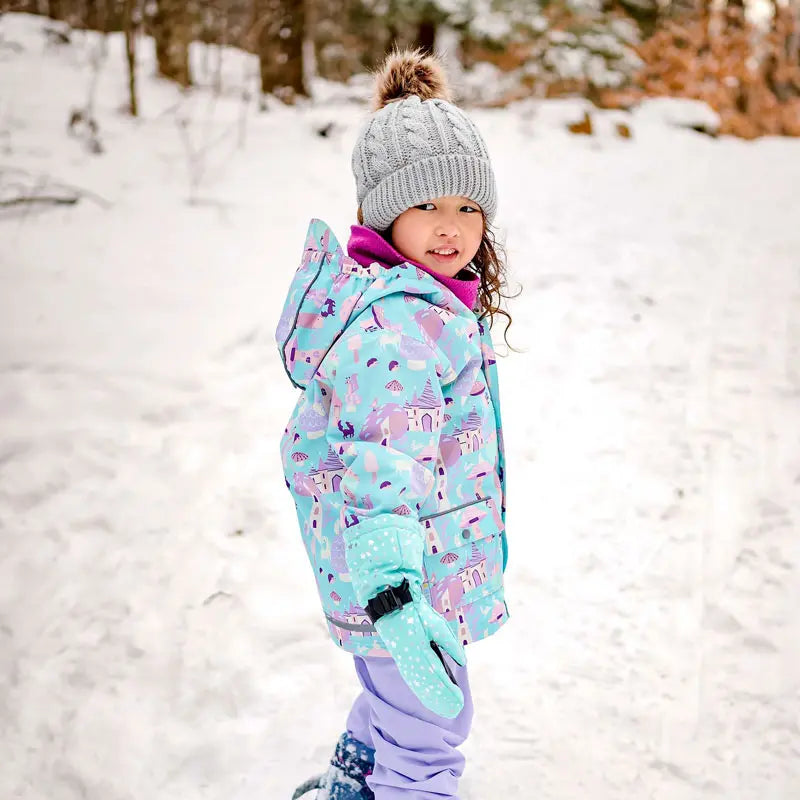Jan & Jul Waterproof Cozy Dry Rain Jacket Enchanted worn by a kid in pastel print, smiling in snowy landscape.