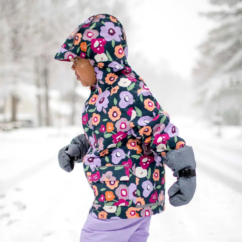 JAN & JUL Waterproof Cozy Dry Rain Jacket Winter Flowers worn by a child running in snowy street with hood up