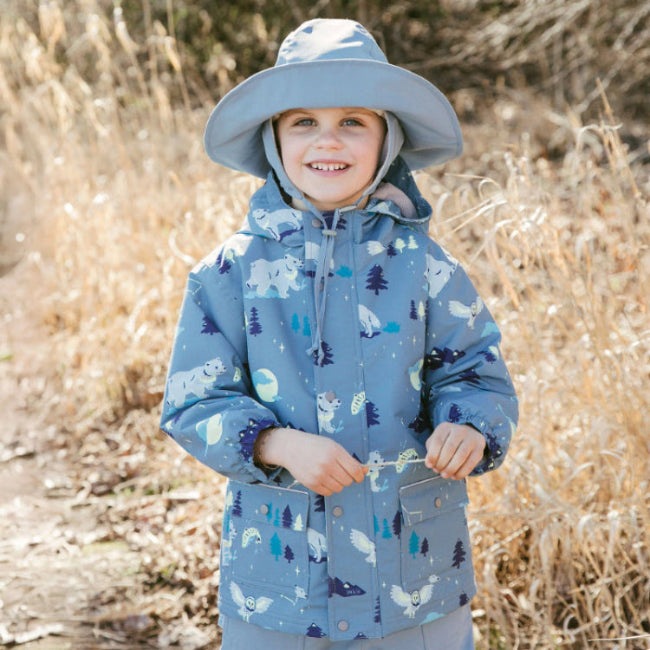 JAN & JUL waterproof kids rain jacket in blue with wolf and bear print, worn by smiling child outdoors