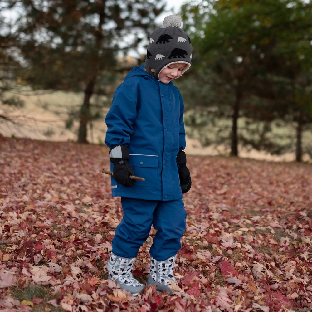 Toddler in blue JAN & JUL Waterproof Cozy Dry Rain Mitten Bear mittens outdoors in autumn leaves, holding a twig.