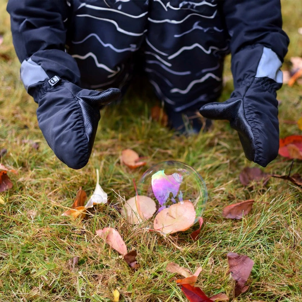 Jan & Jul Waterproof Cozy Dry Rain Mitten Bear navy mittens with gray cuffs, toddler hands reach for a bubble on grass