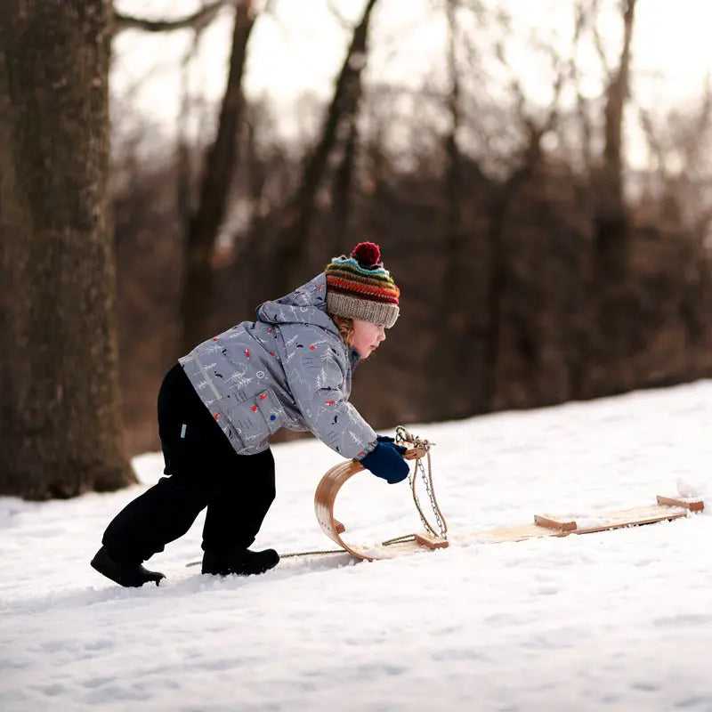 JAN & JUL Waterproof Cozy Dry Rain Pants Black; child in snowy park pulls a wooden sled.