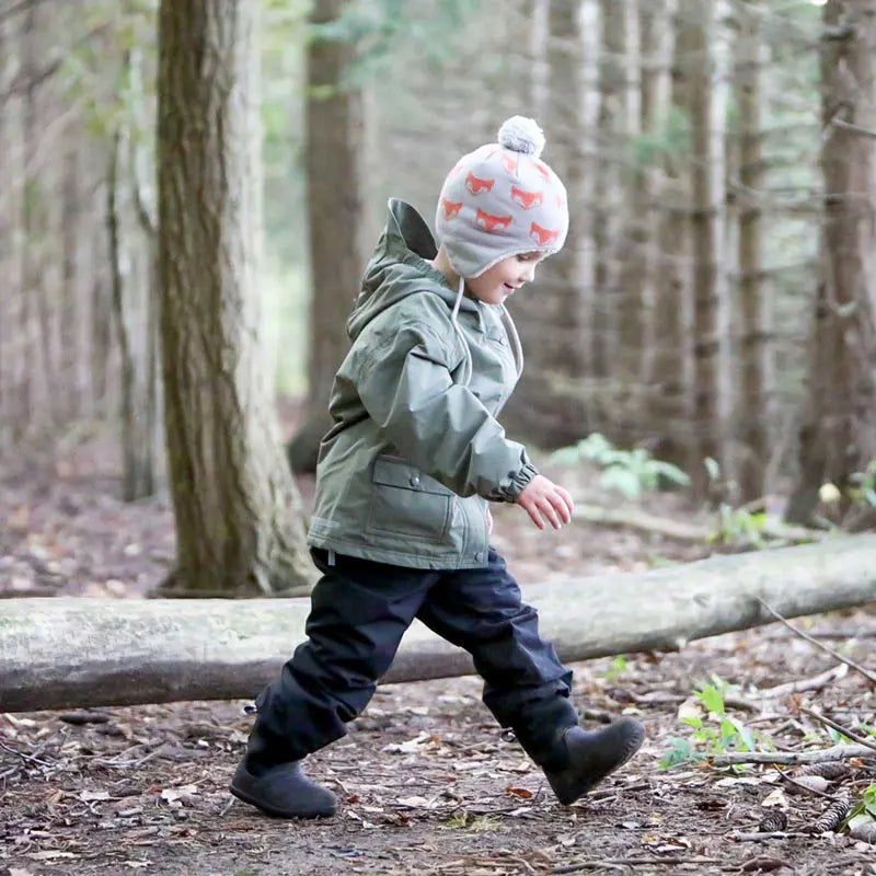 Jan & Jul Waterproof Cozy-Dry Rain Pants Black; toddler walks along a log in a forest wearing them.