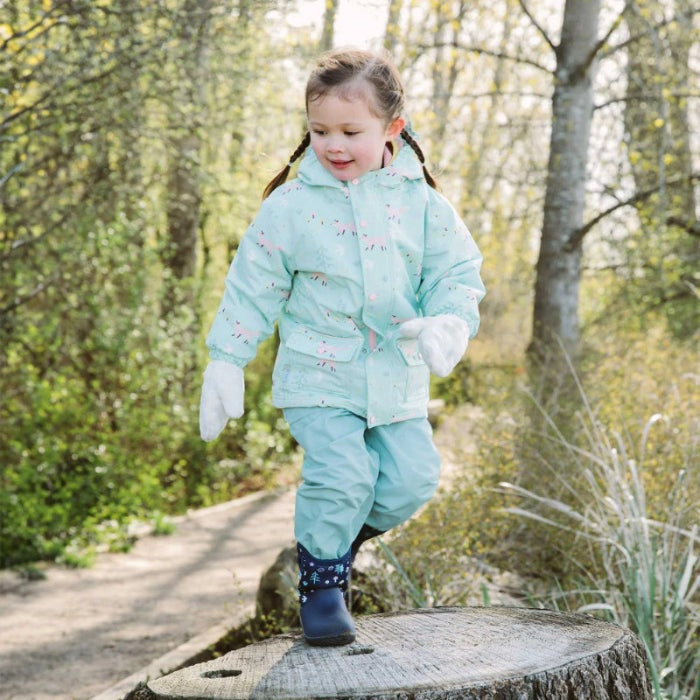 JAN & JUL Waterproof Cozy Dry Rain Pants, Dusty Mint; toddler hops on a stump outdoors, showing waterproof, cozy warmth.