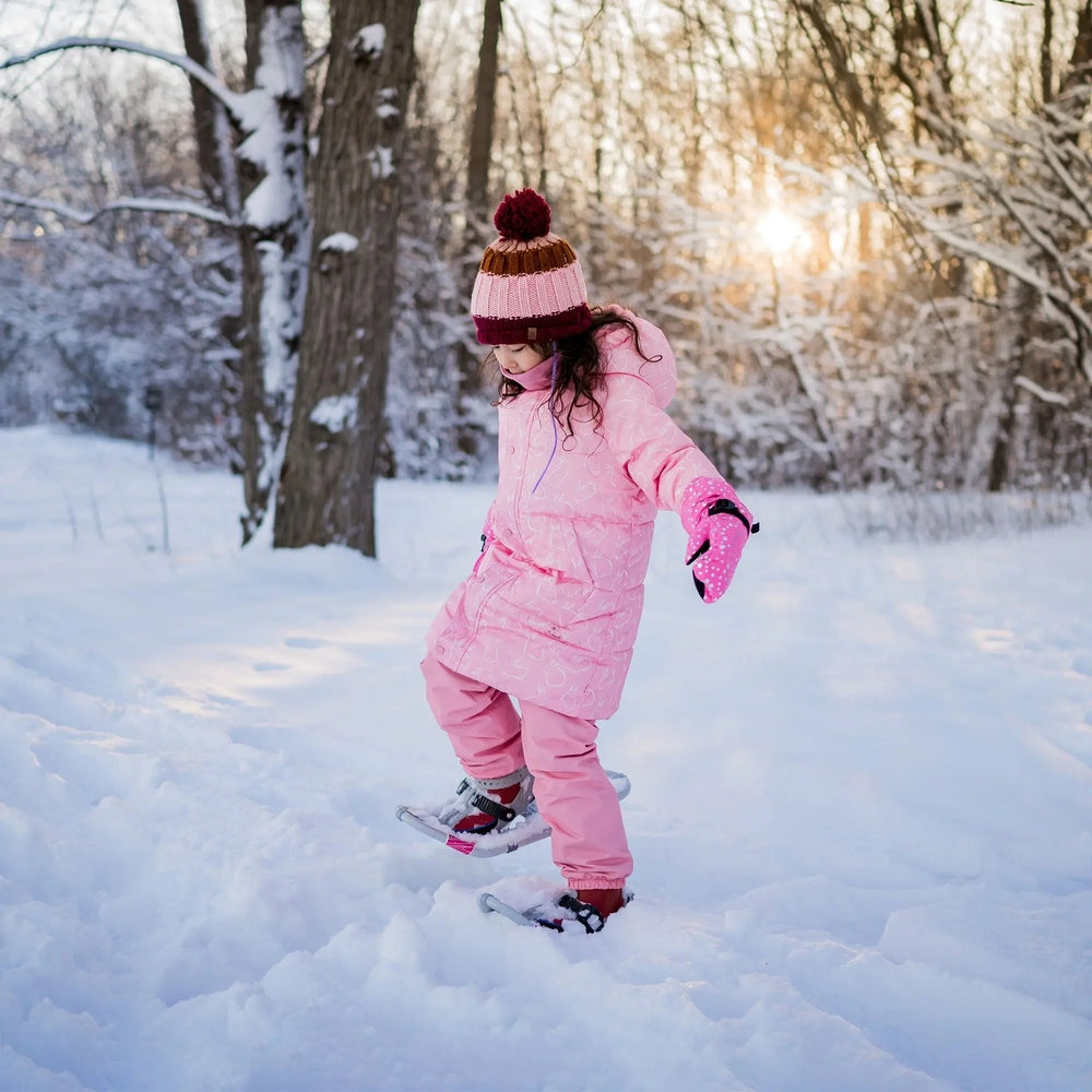 JAN & JUL Waterproof Cozy Dry Rain Pants, dusty pink, worn by a child stepping through fresh snow in a sunlit park.