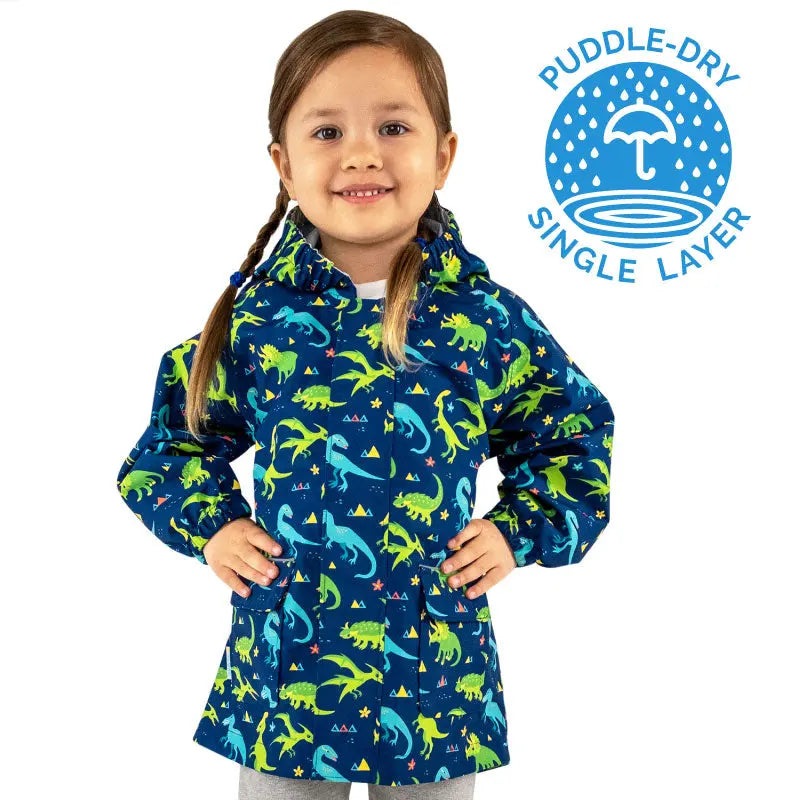 JAN & JUL Dinoland toddler waterproof puddle-dry rain jacket in blue with green dinosaurs; girl wears hood and smiles.