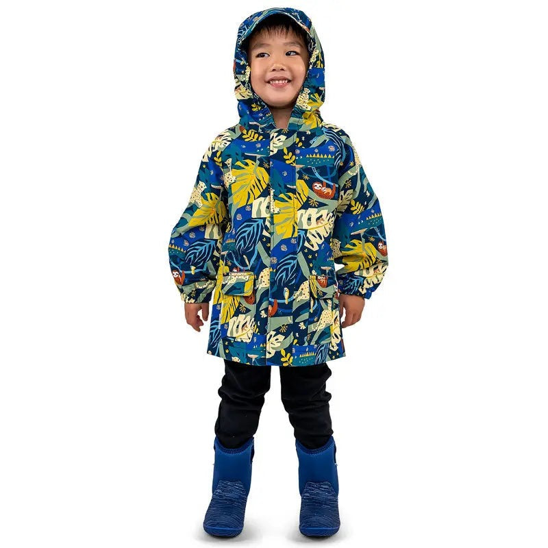 JAN & JUL Jungle Nights waterproof puddle-dry rain jacket worn by smiling kid with hood in blue-yellow leaf print