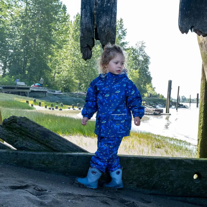 JAN & JUL Waterproof Puddle-Dry Rain Pants Constellations worn by toddler exploring a muddy shoreline in blue.
