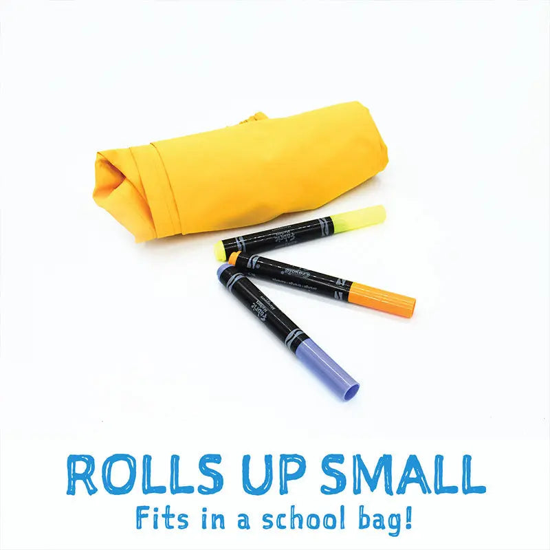 JAN & JUL Dreamscape Waterproof Rain Pants rolled compactly beside neon highlighters, showing it fits in a school bag.