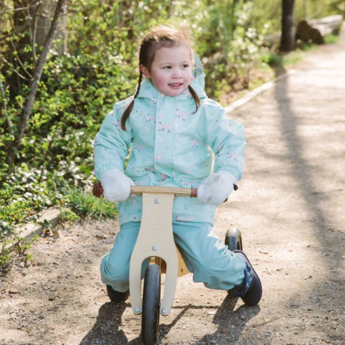 Jan & Jul Waterproof Puddle Dry Rain Pants in dusty mint, toddler riding a wooden balance bike.