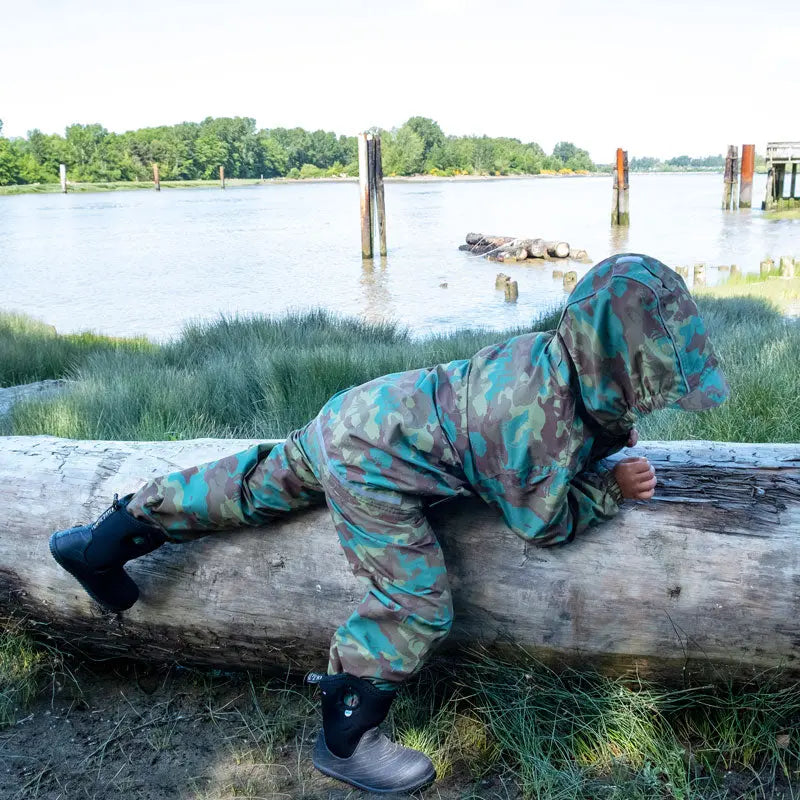 Jan & Jul Waterproof Puddle-Dry Rain Pants Woodland Camo on a toddler crawling along a log by the water.