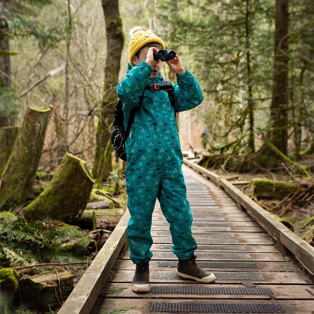 JAN & JUL teal Waterproof Puddle-Dry Rain Suit on a child, exploring a forest boardwalk with binoculars.