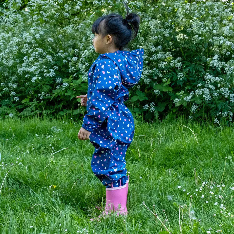 Jan & Jul Waterproof Puddle Dry Rain Suit Terrazzo, blue with pink specks, shown on a child running through a grassy field.