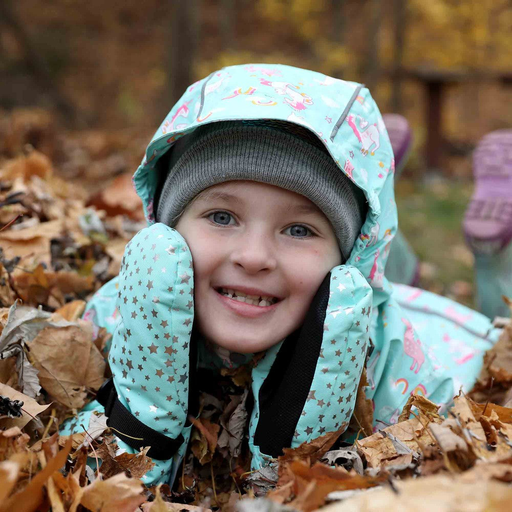 Jan & Jul Waterproof Toasty Dry Mitten Mint Star on a smiling toddler’s hands as she digs through autumn leaves.