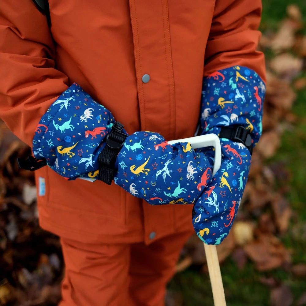 Jan & Jul Space Dinos waterproof toddler mittens in blue with adjustable straps worn on a bright orange coat.