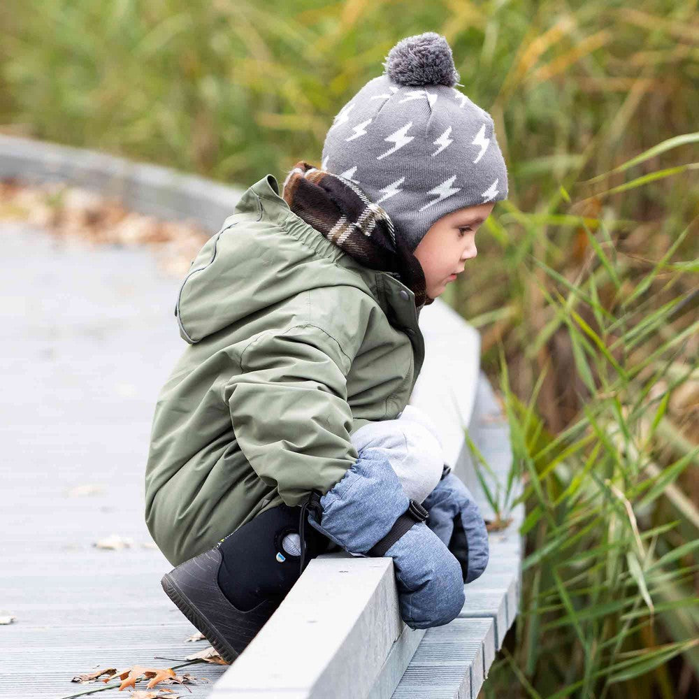 JAN & JUL Waterproof Toasty Dry Mitten Thumb Heather Grey on a toddler perched, showing warm, padded mittens gripping the railing.