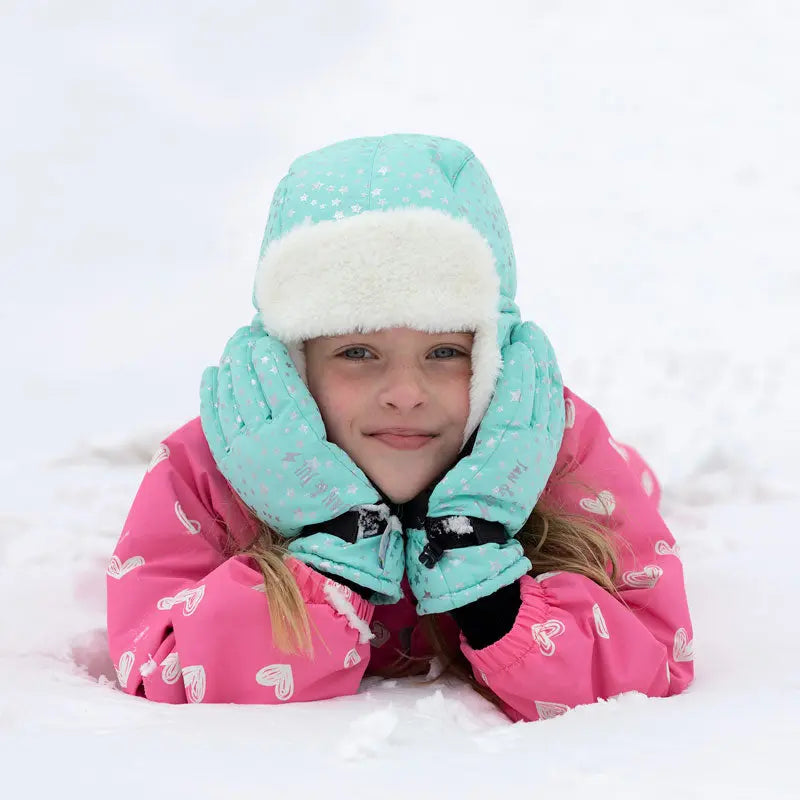 JAN & JUL Waterproof Toasty Dry Snow Gloves Pink Star worn by a smiling toddler lying in the snow with hands on cheeks
