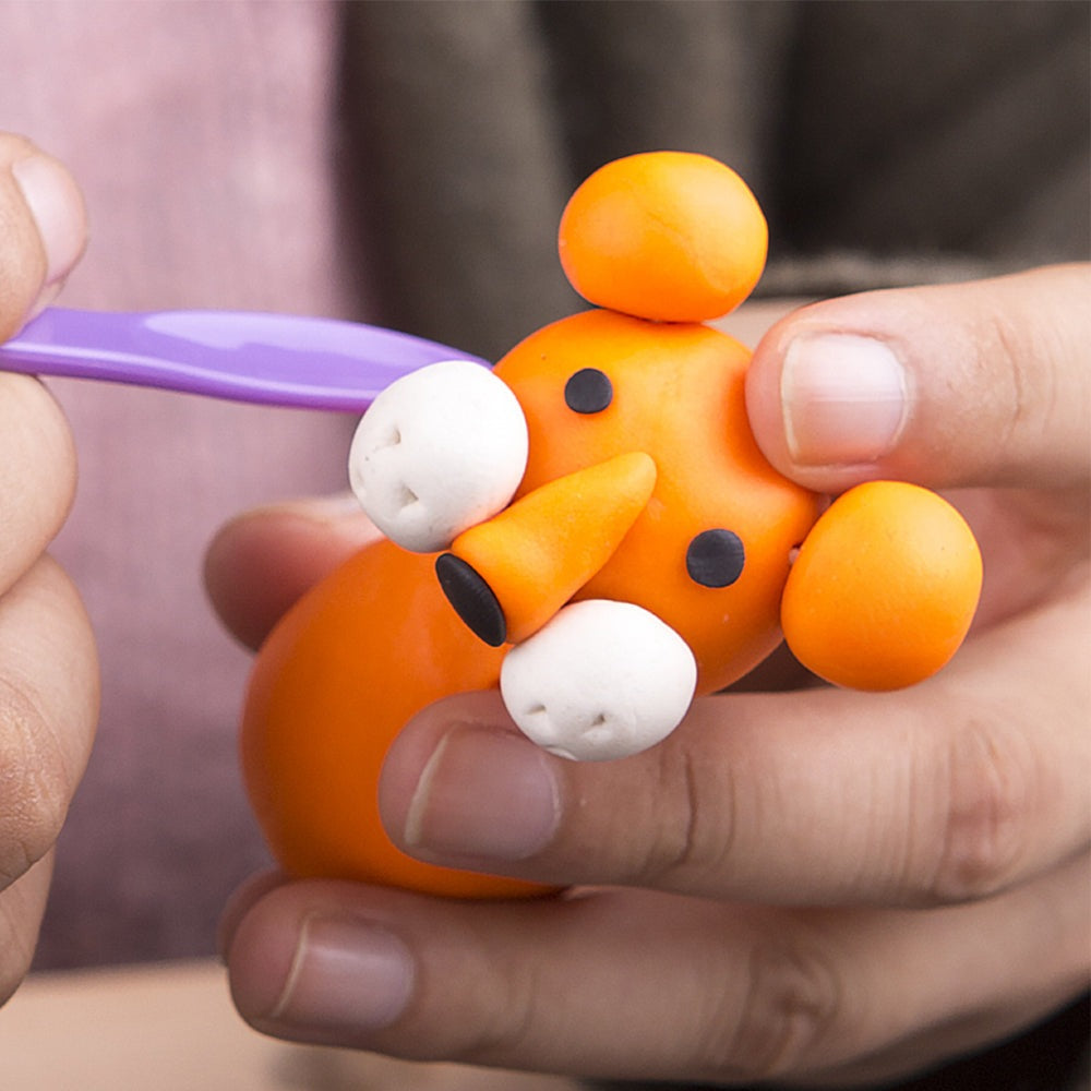Jar Melo modeling playdough set; orange figure being molded with a purple tool, 12 colors included