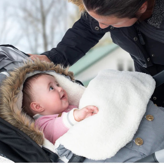 Juddlies infant car seat/stroller bag in salt and pepper grey with faux fur trim, baby resting inside.