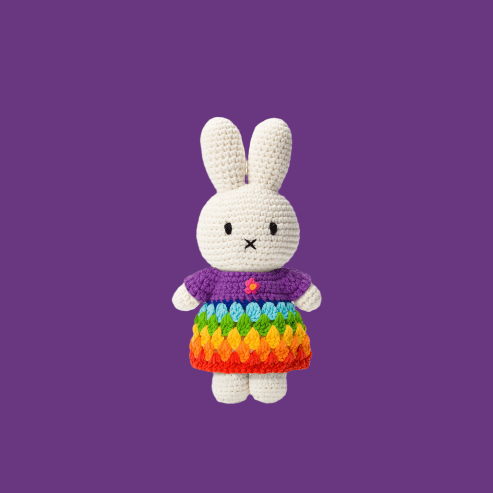 Just Dutch Miffy plush rabbit in rainbow crocheted dress on purple background