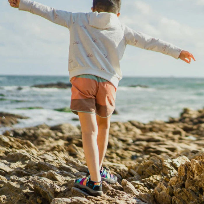 KEEN Newport H2 big-kids sandal, multicolor rugged water sandal worn by child on rocky beach