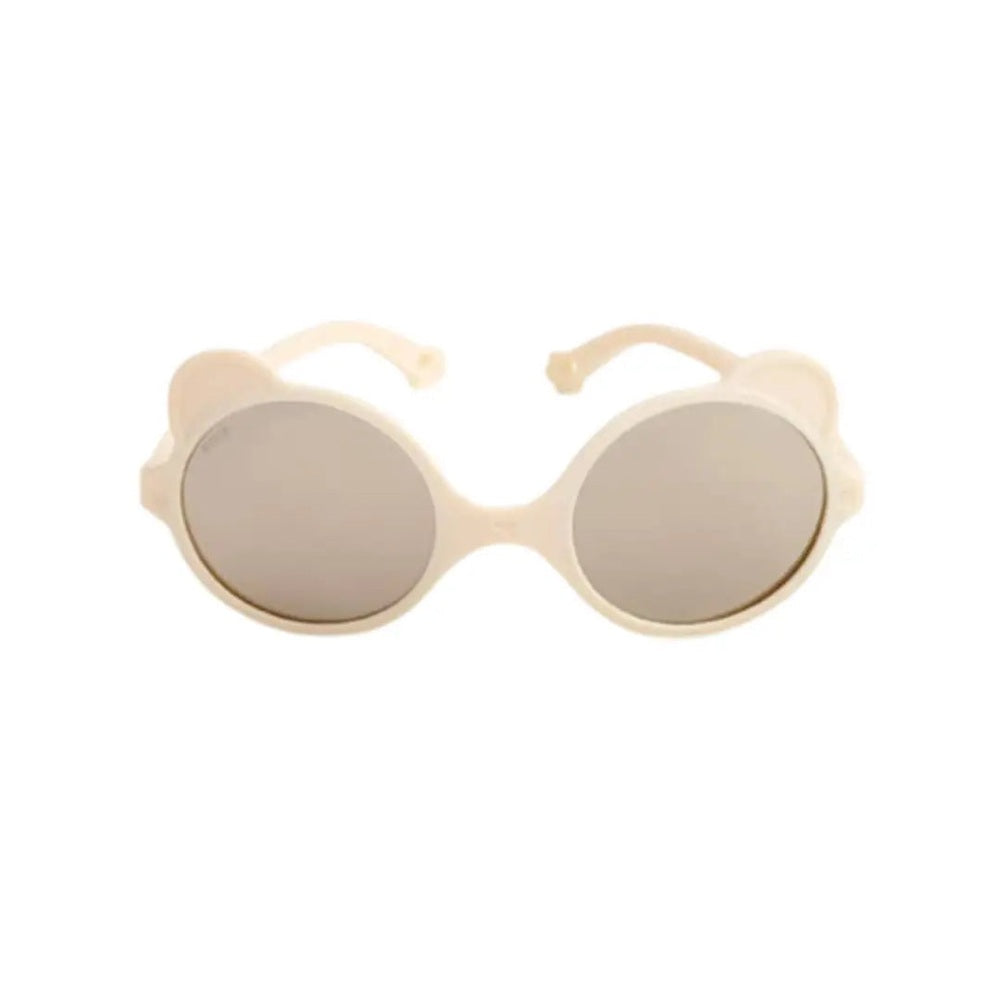 Ki Et La Ourson Cream baby sunglasses with round cream frames and gray lenses being worn by a baby.