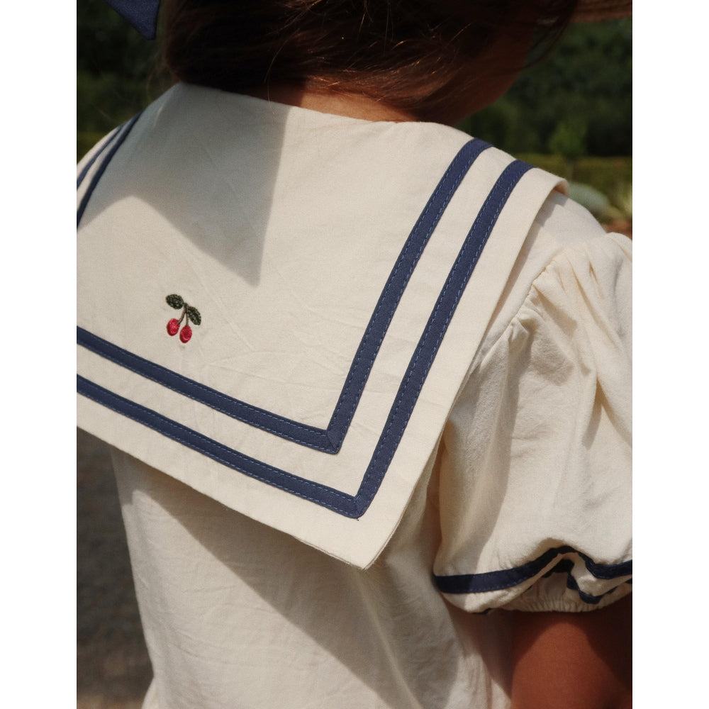 Konges Slojd Allie Sailor Dress optic white with navy trim; back view shows cherry embroidery and oversized sailor collar.
