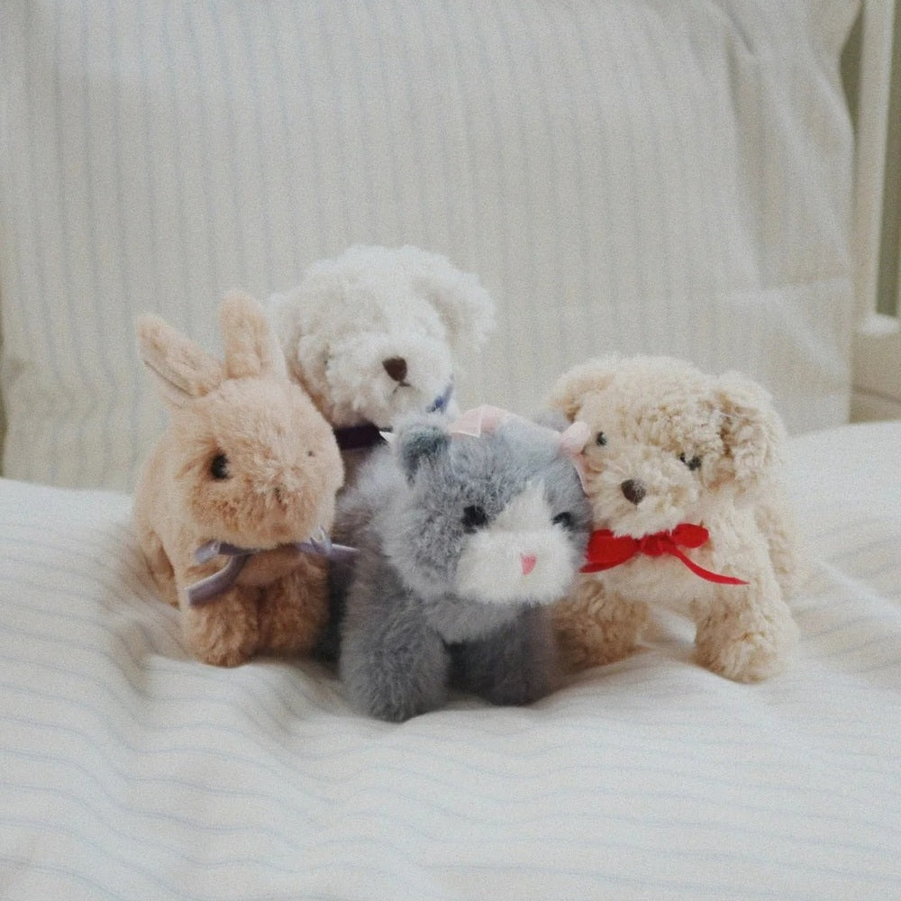 Konges Slojd Baby Animals plush set of four soft toys arranged on a striped bed.