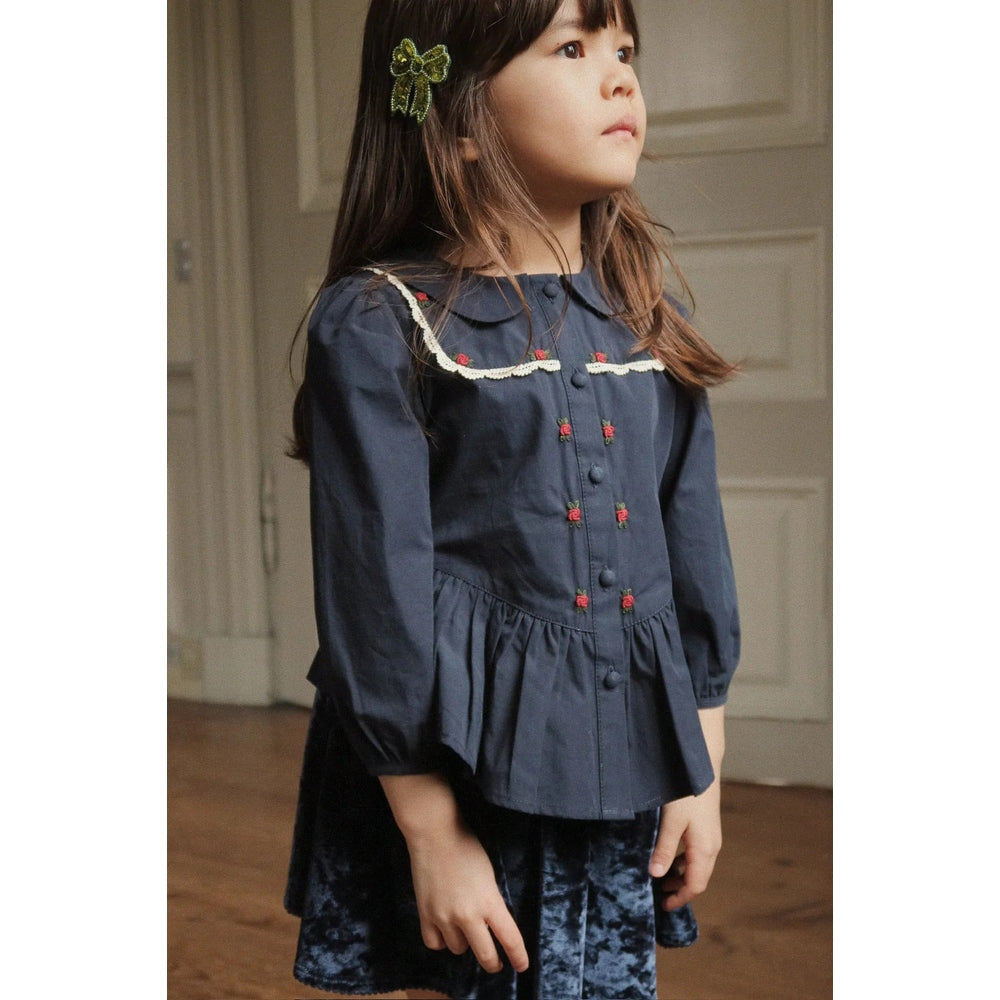 Konges Slojd Carlito Skirt Navy in velvet, worn by a girl standing indoors with hands by her sides.